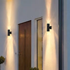 Modern outdoor wall lights on a building exterior with a door and window.